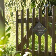 Ein Holzzaun mit einem Schild, das den Garten der Psychosomatischen Klinik kennzeichnet.